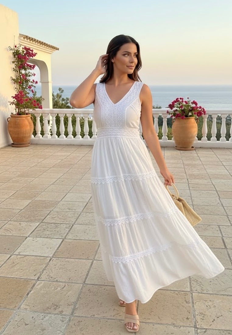 Woman in a white halter cotton dress from coral secret, standing on a balcony with ocean view