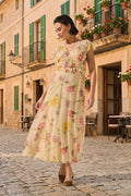 Antique Rose Boutique yellow floral chiffon long dress with V-neck and frill details worn by a woman outdoors.