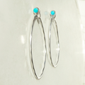 Silver hoop earrings with turquoise stones on a light background