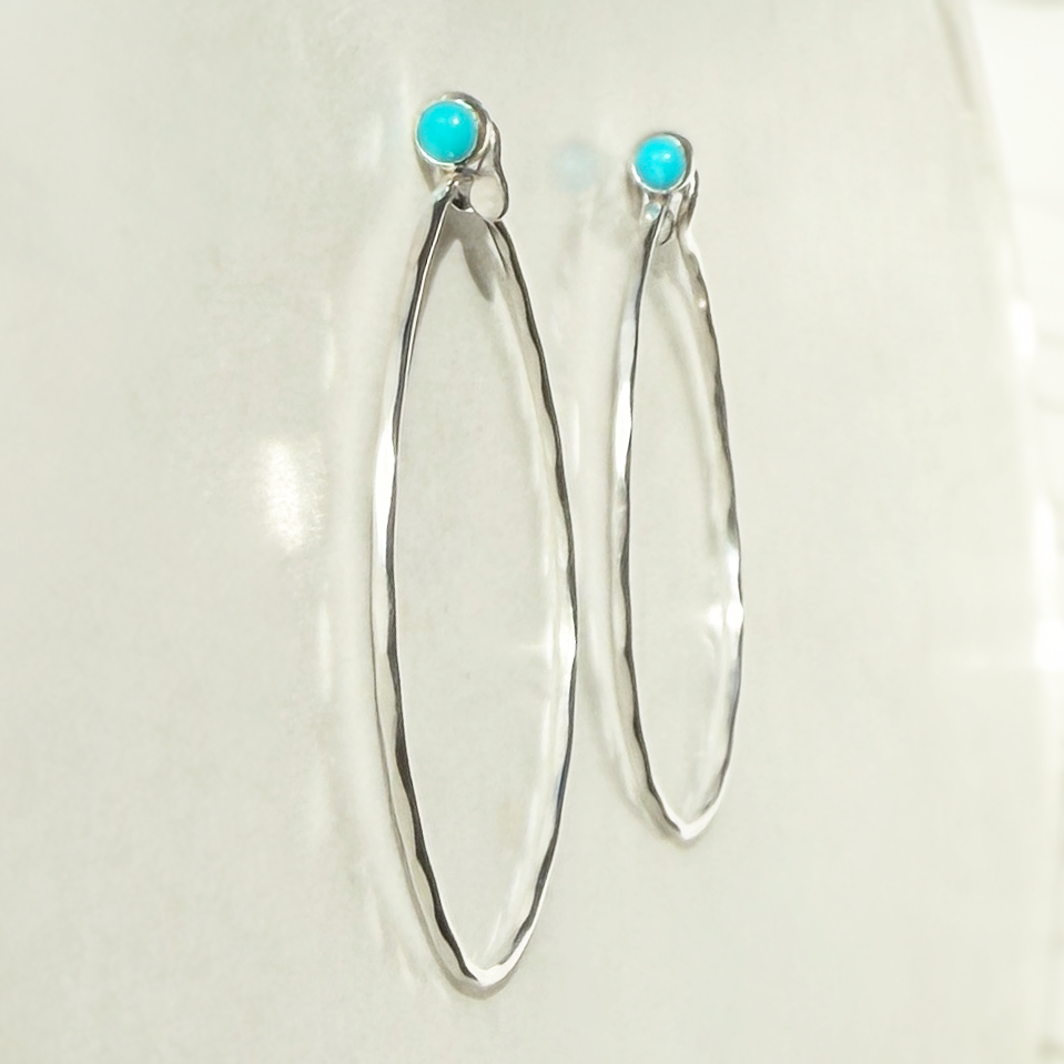 Silver hoop earrings with turquoise stones on a light background