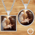 a necklace pendant with a painting of a baby Jesus in a manger, surrounded by the parents, likely the mother and father.