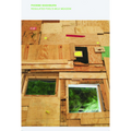 Eine aus verschiedenen Holzstücken und Sperrholzplatten zusammengesetzte Wand. In der Wand befinden sich zwei fensterähnliche Öffnungen, die den Blick auf leuchtend grünes Gras freigeben.